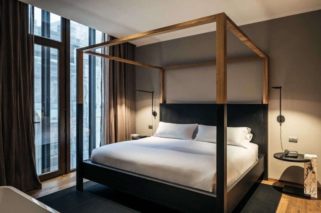 A four-poster bed in front of floor-to-ceiling windows in a Suite at Hotel Magnolia, Santiago, Chile