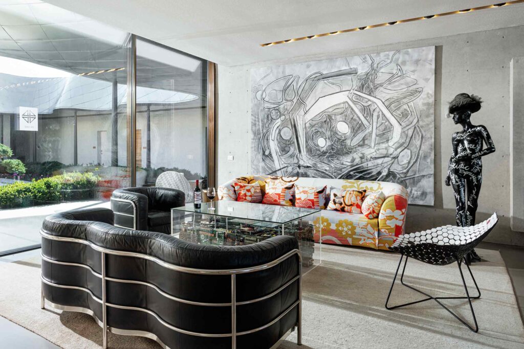 A black couch and contemporary furnishing and art in a light-flooded room in Chilean Cachapoal