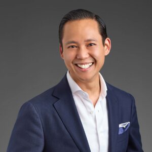 Portrait of Nick Liang, Director of Operations at the Puli Group. Nick is a Chinese man and wears a blue suit, white shirt and blue pocket square