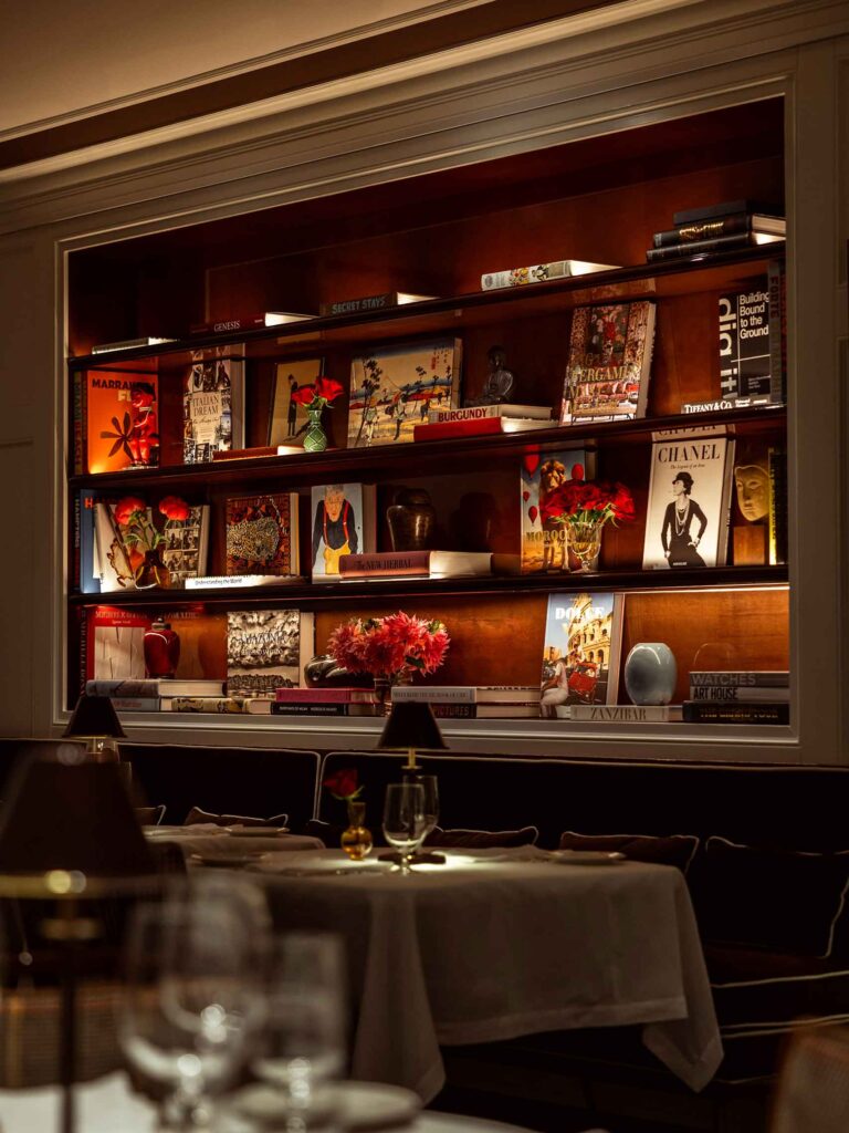 Books and flowers sit on a lit shelf inside Casa Tua in New York City