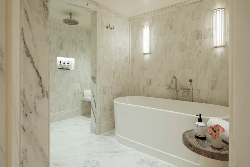 White marble bathroom at The Surrey, New York with walk-in shower and bathtub