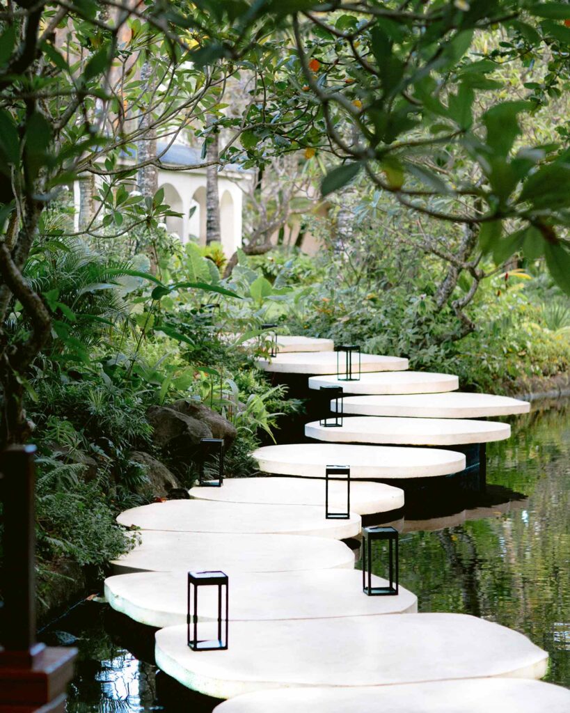 A walkway over a body of water and surrounded by lush vegetation leads to the Guarlain Spa at One&Only Le Saint Géran, Mauritius