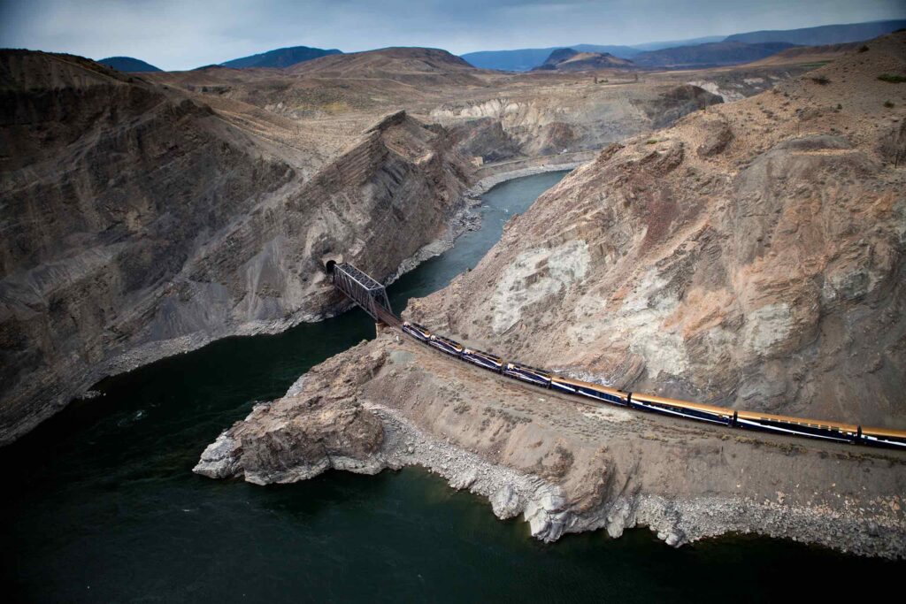 A luxury train crosses a river via a steel bridge in the Okanagan Valley, Alberta, Canada