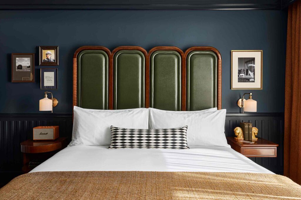 A khaki leather and wooden headboard of a double bed against a dark blue wall at The Manchester, Lexington, Kentucky, USA