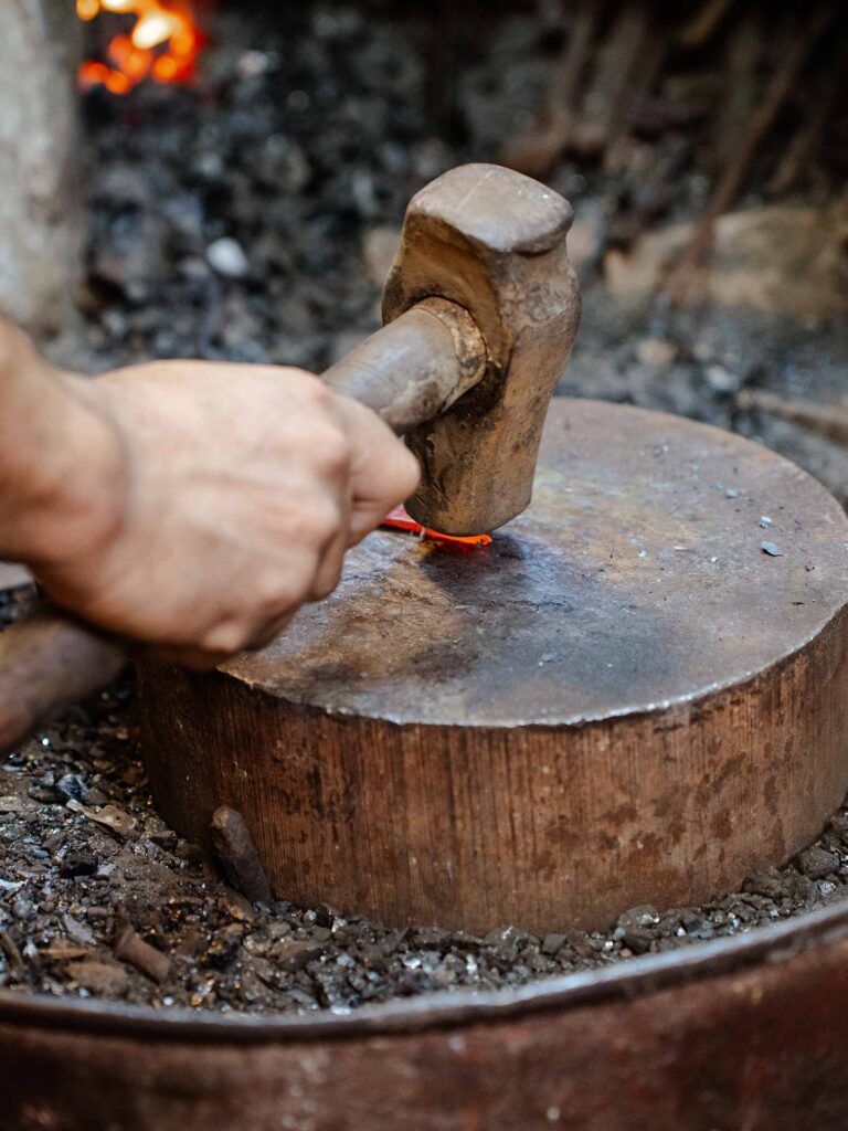 The ancient art of Moroccan copper forging with a heavy hammer hammering the copper into a flat piece