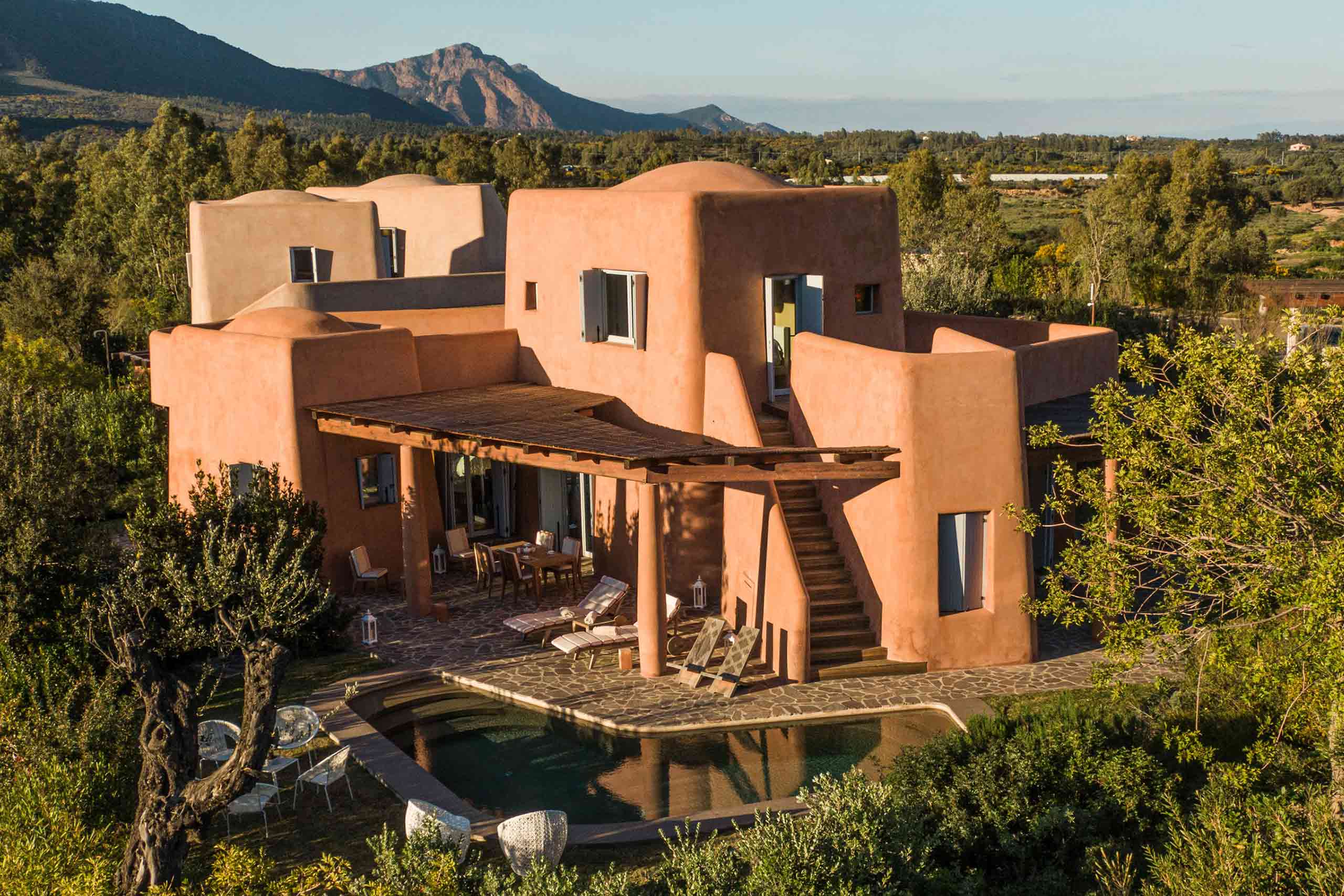 Villas at Is Molas, Sardinia – Massimiliano Fuksas designed villa, a striking orange villa amid greenery with mountains in the background