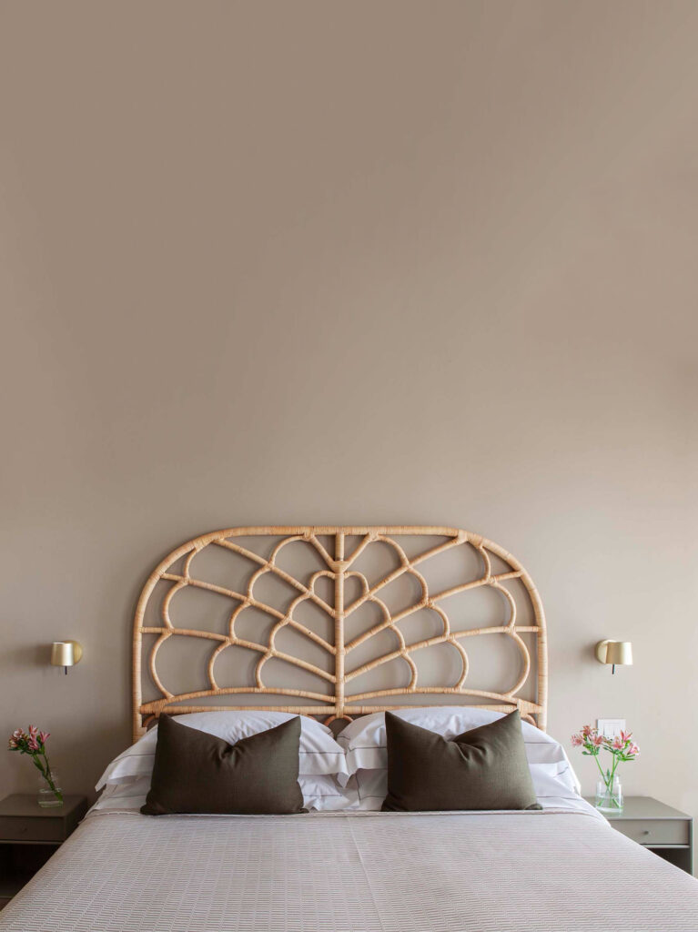 Bed with green scatter cushions and a retro rattan headboard