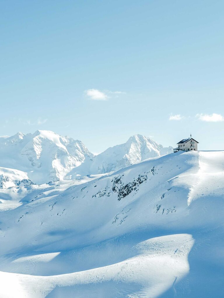 A lone church sits on a snowy peak in the Dolomites