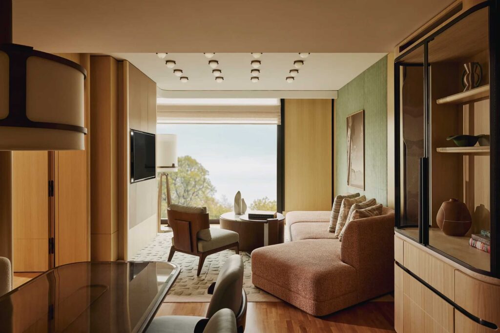 Andre Fu designed living room, featuring honey coloured wood panelling, bespoke cabinets and rust coloured sofa looking out over Hyde Park