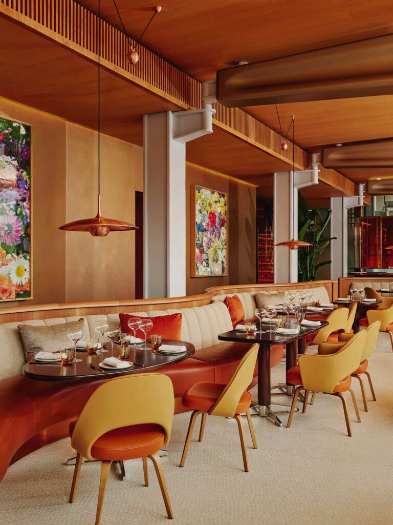 Damien Hirst floral paintings line the walls, with red mid-century modern design tones and wood panelling at abc kitchen in London