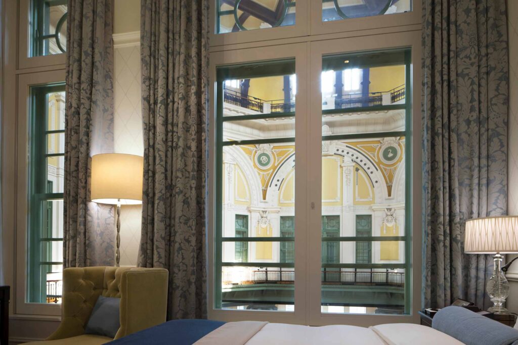 A bedroom window at The Tokyo Station Hotel looking out to yellow, European architectural interiors of the old station building