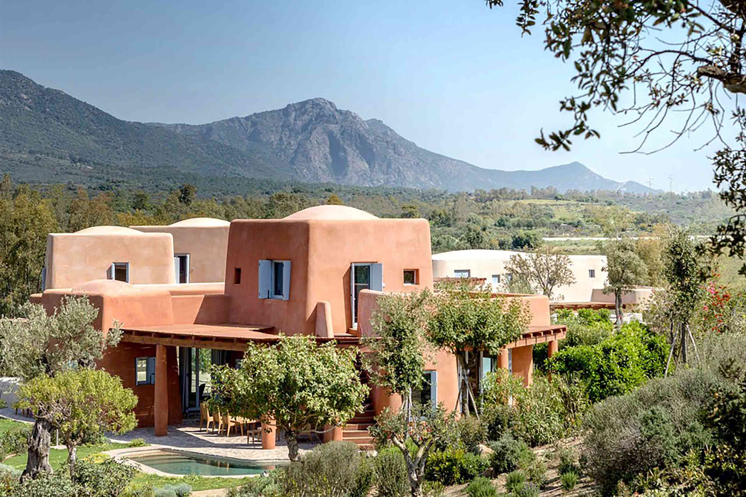 Villas at Is Molas, Sardinia – Massimiliano Fuksas designed villa, a striking orange villa amid greenery with mountains in the background