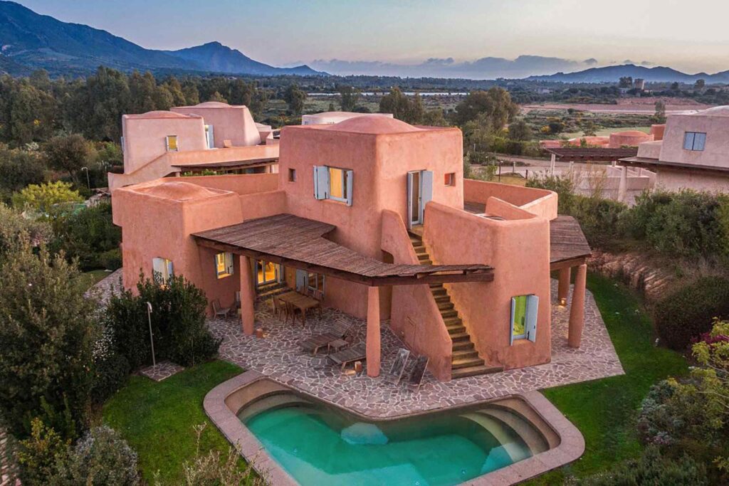 Villas at Is Molas, Sardinia – Massimiliano Fuksas designed villa, a striking orange villa with a private pool amid greenery with mountains in the background