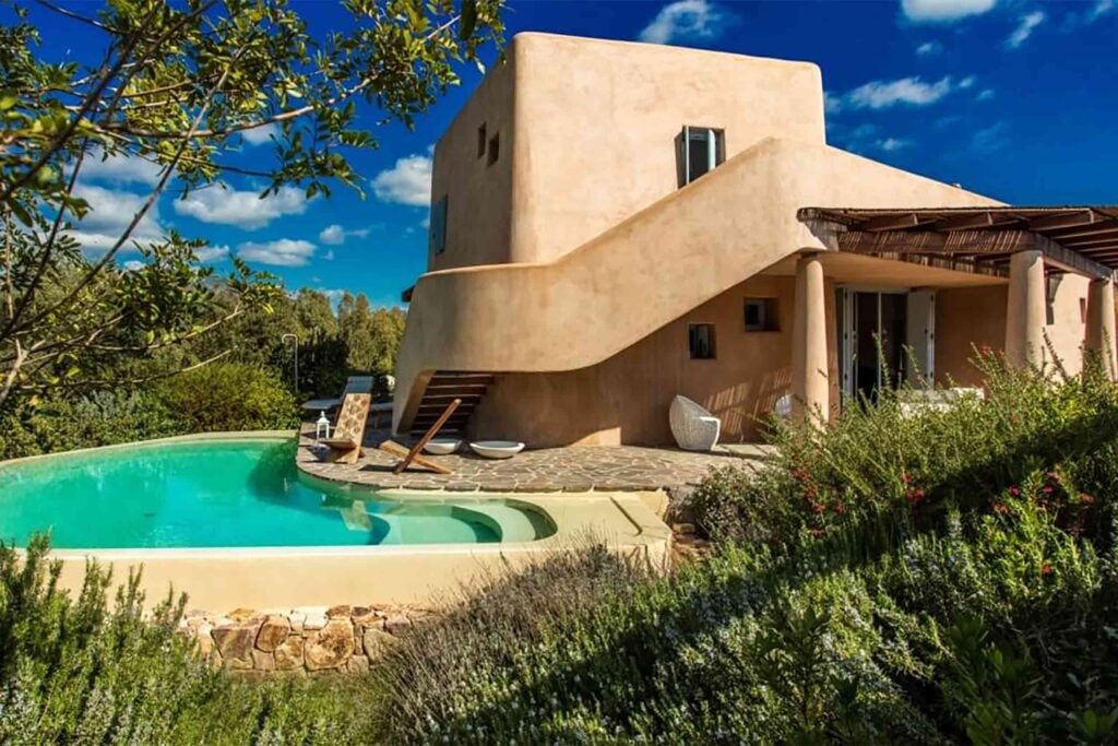 Exterior shot at Villas at Is Molas, Sardinia – with sand coloured villa curving around a private pool