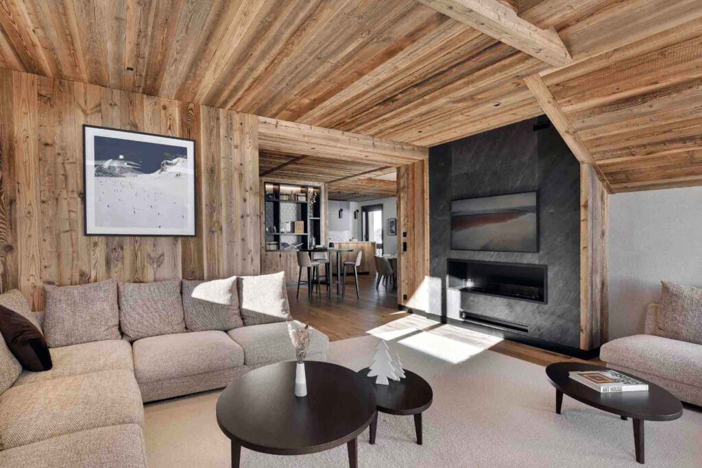Modern chalet interiors with wood-panelled walls, a black fireplace and a seating area at the front at Antarès Méribel, Méribel, France