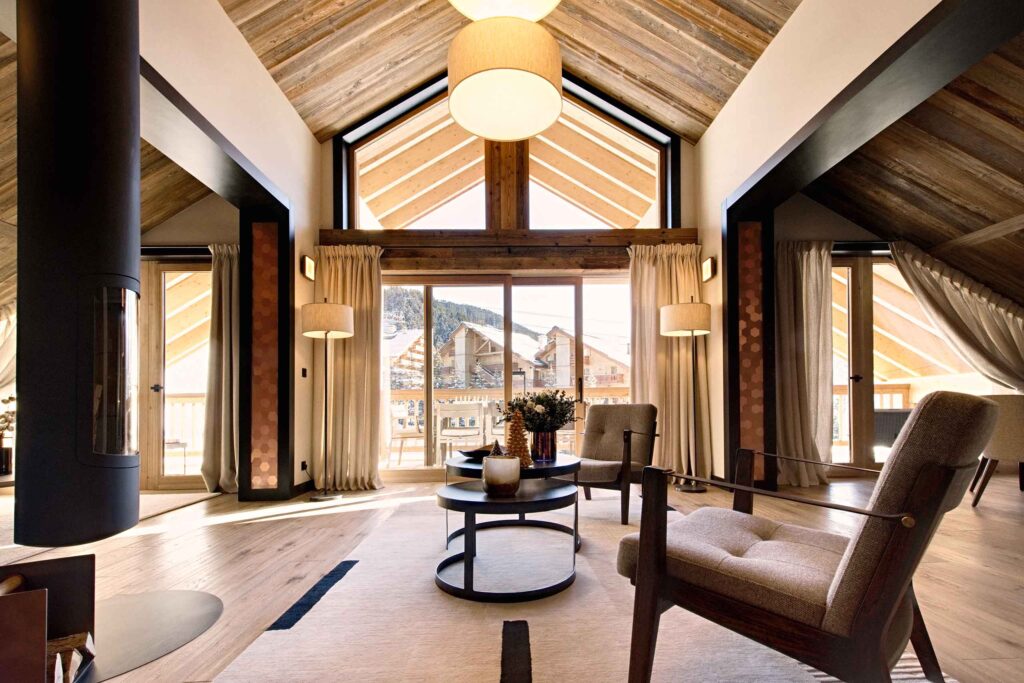 Chalet-style living with a seating area and a contemporary, hanging fireplace at Antarès Méribel, Méribel, France