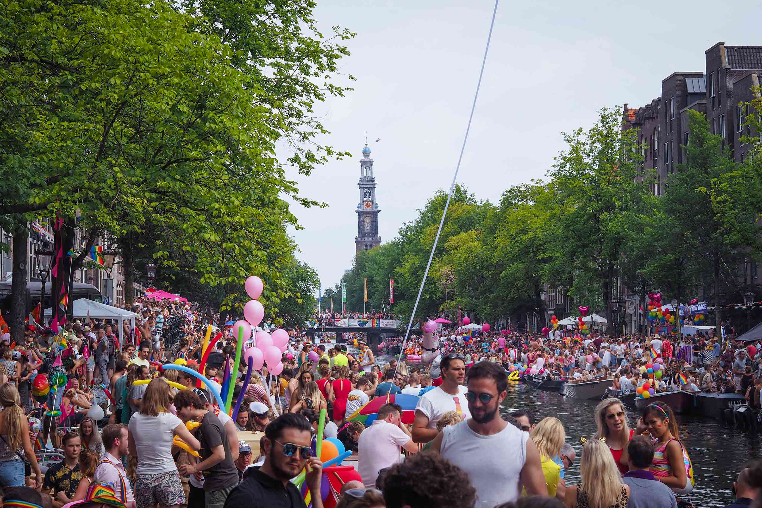 A large crowd of people celebrate WorldPride 2026 on a canal in Amsterdam, The Netherlands