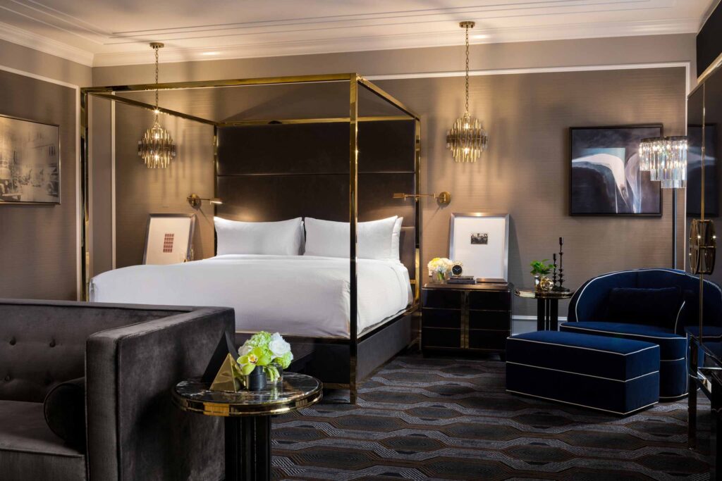 A golden four-poster bed on a patterned, dark carpet of the Lt. Governor Bedroom at Fairmont Hotel Vancouver, Canada
