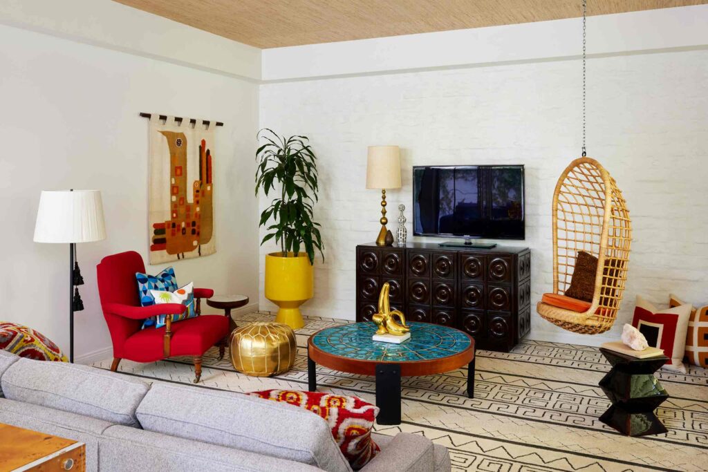 Colourful Villa interiors at Parker Palm springs, crimson armchair, gily gold pouffee, mid century armoir, hanging rattan chair, geometric carpets