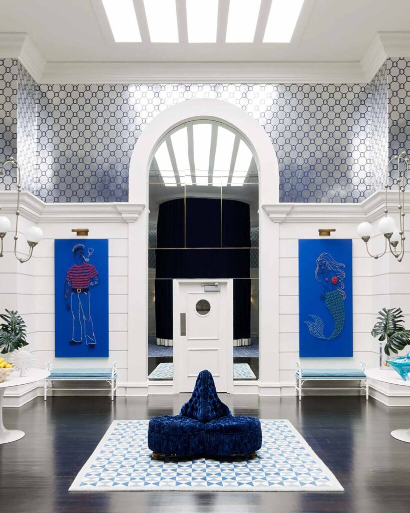 The PSYC – Palm Springs Yacht Club, Parker Palm Spring's nautical themed spa. Colourtheme is blue and white. The picture is of the spa reception, seating, sailor and mermaid paintings and a door that leads to the spa area