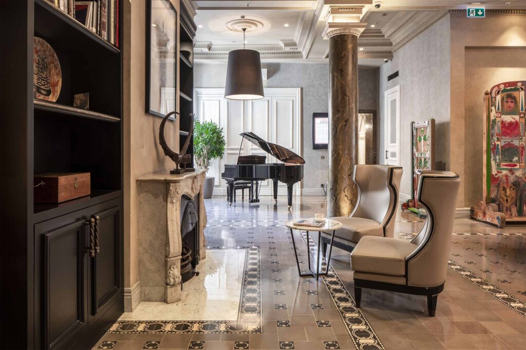 A piano, two chairs and a fireplace inside the lobby of The Bank Hotel Istanbul, a Member of Design Hotels, Istanbul, Türkiye