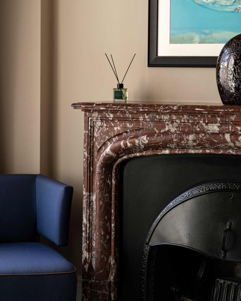 Detail of a marble fireplace with a stylish blue chair