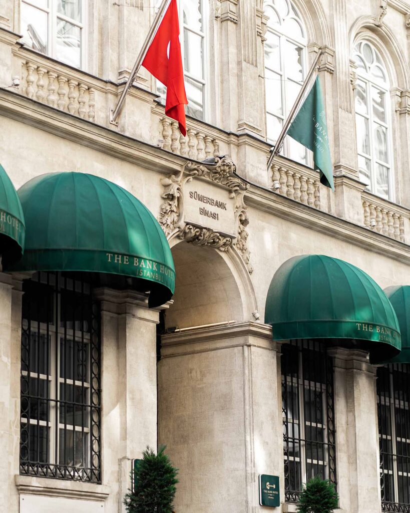 Flags above the entrance of the Neo-Renaissance facade of The Bank Hotel Istanbul, a Member of Design Hotels, Istanbul, Türkiye
