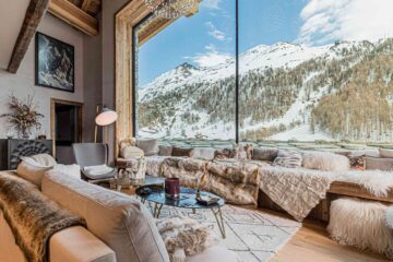 The Luxury Chalet Company chalet featuring expansive floor to ceiling window views of the mountain, with wool and deerskin interiors