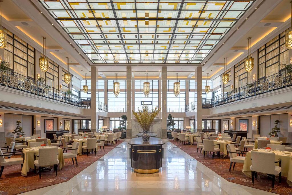 The Lobby restaurant with an Art Deco ceiling and a glass-fronted wall towards the back, at The Peninsula, Istanbul, Türkiye
