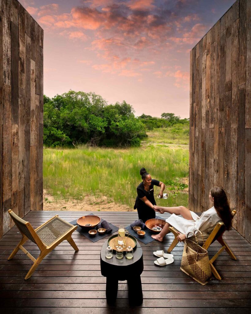 A spa therapist washes the feet of a female guest with a view of the bush in KwaZulu-Natal, South Africa