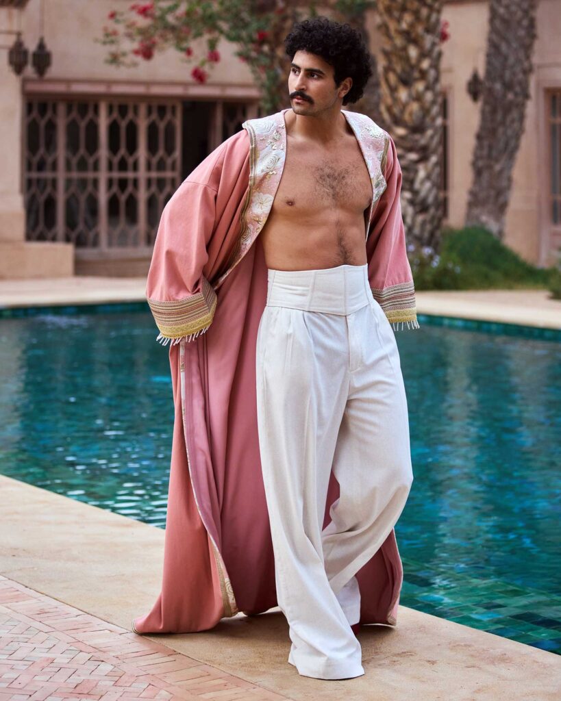 Amran Bennaji wears a pink embroidered canvas Hilal kimono while walking past a pool at Jnane Rumi in Marrakech, Morocco