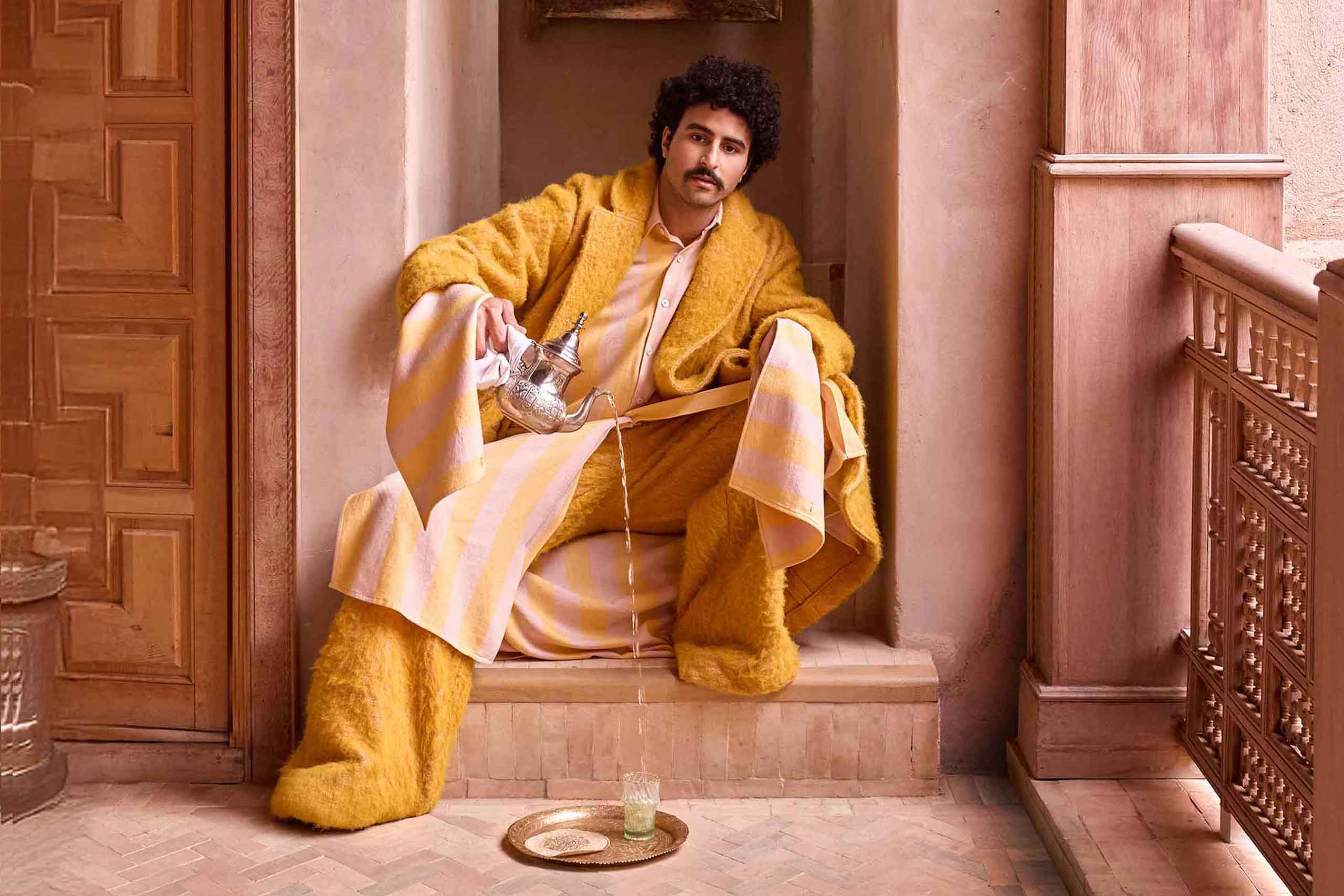 Amran Bennaji pours tea into a beldi glass on a golden tray in Marrakech, Morocco
