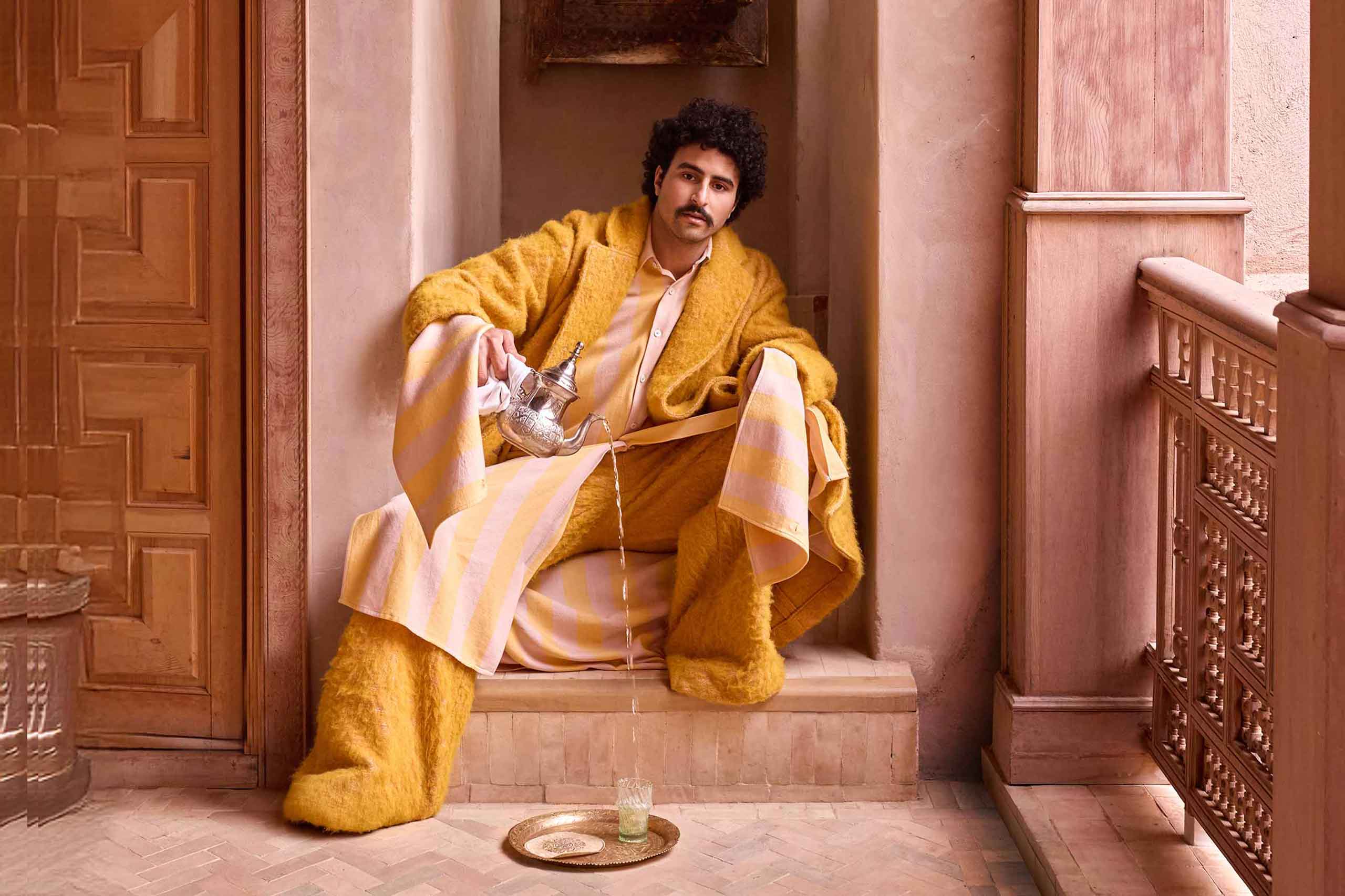 Amran Bennaji pours tea into a beldi glass on a golden tray in Marrakech, Morocco