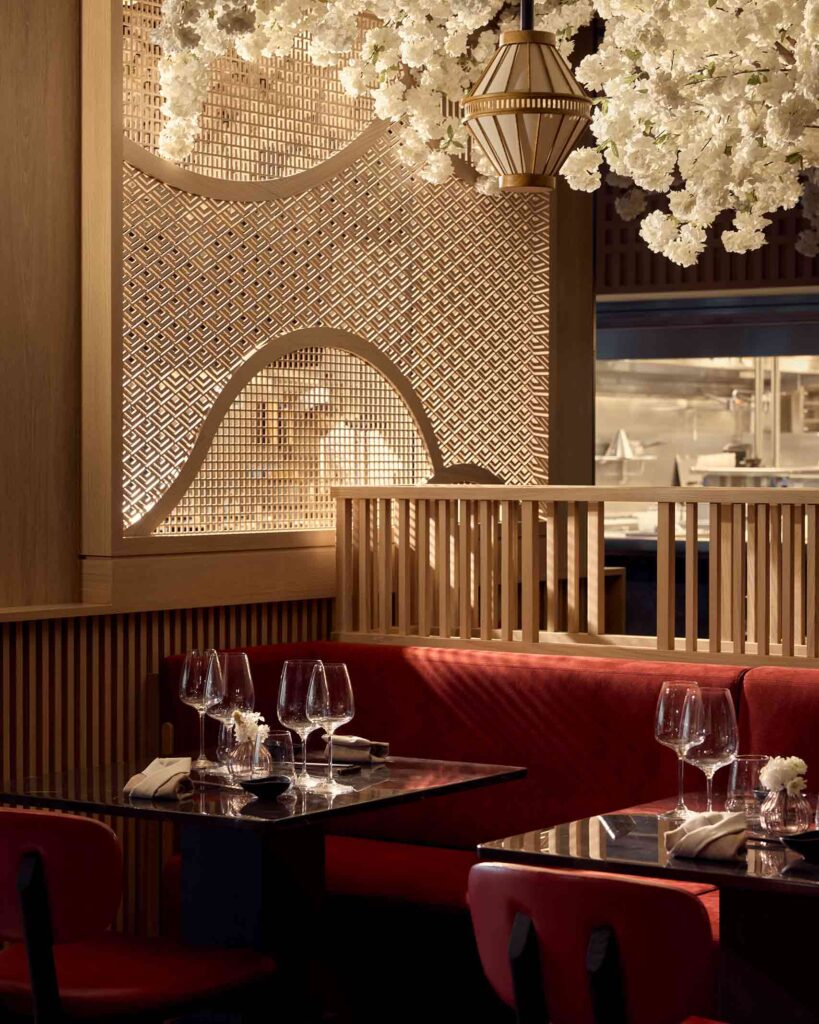 Sakura pan-Asian restaurant on Explora Journeys ships – red searing, laid black tables and white sakura flowers and lanterns hanging from the ceiling