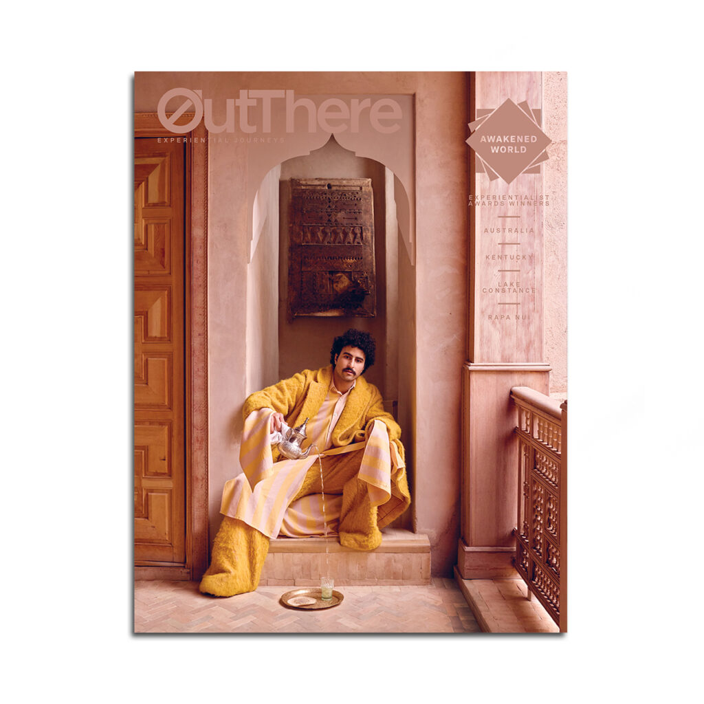 The Awakened World Issue of OutThere magazine, featuring a model pouring tea into a beldi glass while sitting beneath an ornate doorframe in Marrakech, Morocco