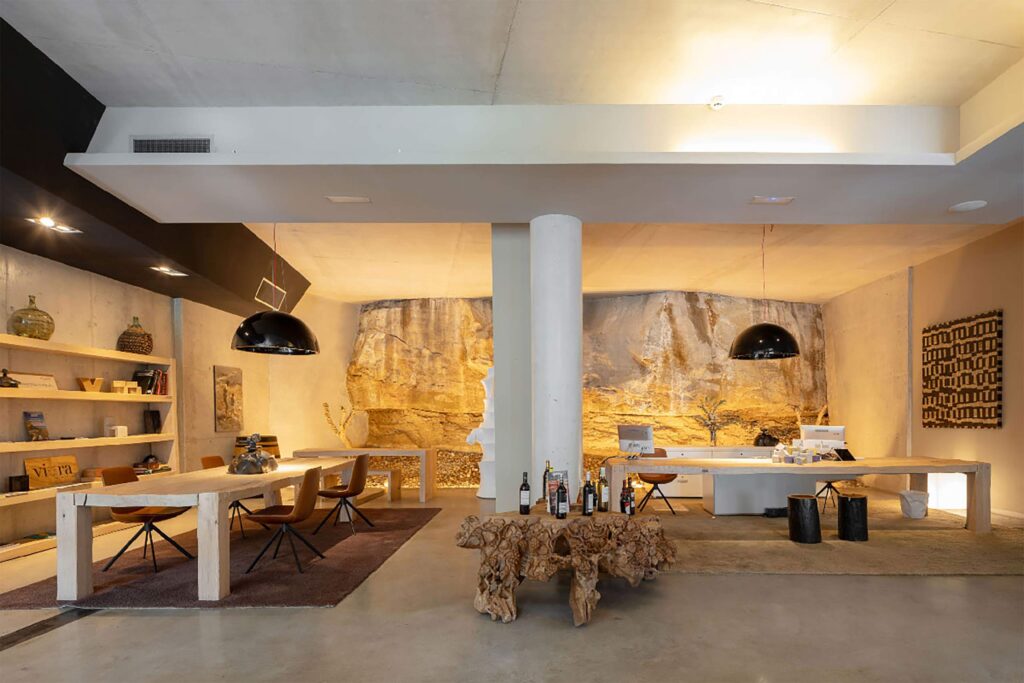 Hotel Viura reception area featuring exposed rock wall, sculptural wooden furniture and warm, minimalist industrial design.