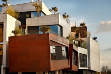 Exterior of Hotel Viura showing stacked cuboid architecture with concrete and rust-coloured facades and rooftop terraces.
