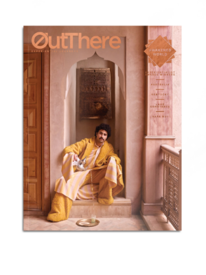The Awakened World Issue of OutThere magazine featuring a Moroccan model dressed in a yellow Moroccan designed outfit sitting in a Arabesque doorway