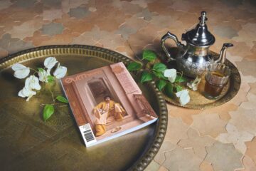 The Awakened World Issue of OutThere magazine sits on a brass tray, alongside it a Moroccan teapot and white flowers