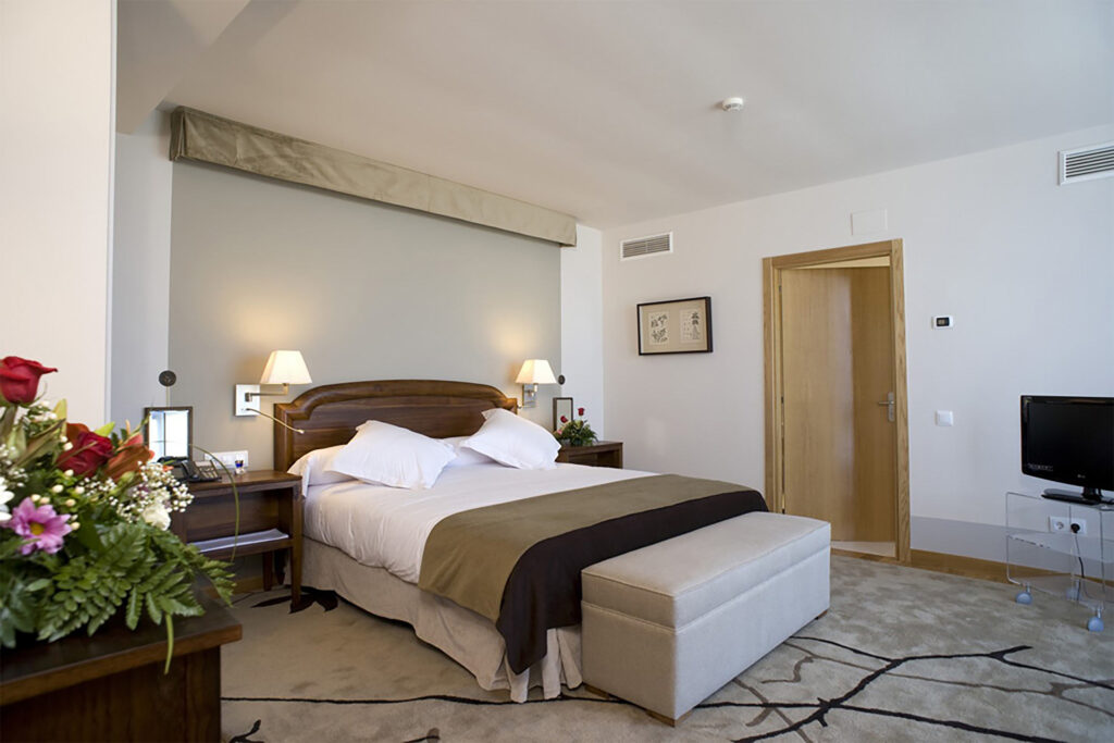 Spacious bedroom at Parador de Argómaniz with wooden furnishings, large bed, soft lighting and neutral décor.