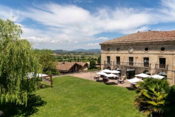 Historic countryside hotel surrounded by landscaped gardens and terrace seating overlooking the Basque landscape.