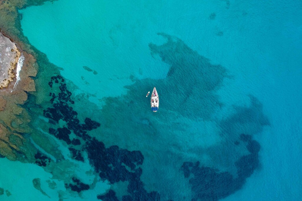 Birdseye view of a white yacht on clear blue waters off the coast of Mallorca, Spain – summer travel with Scott Dunn