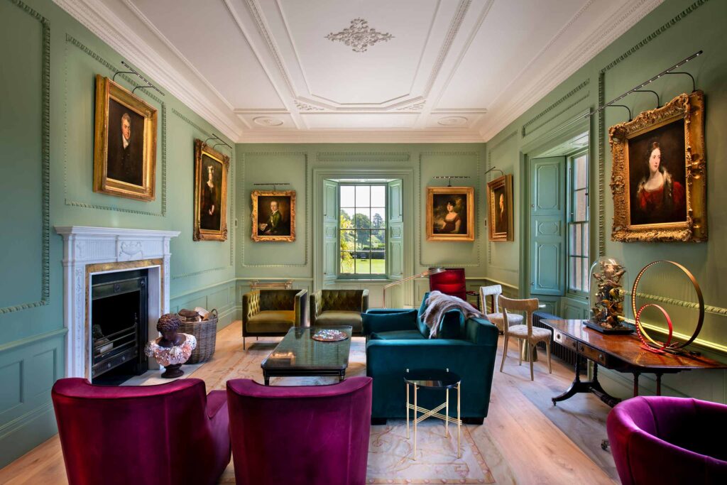 A pistachio-coloured drawing room with contemporary furnishings and oil portraits of previous inhabitants of Hadspen House in Bruton, UK