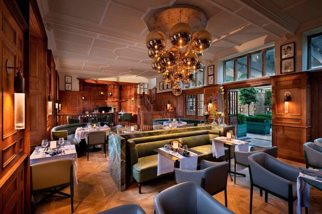 The Botanical Rooms restaurant with its oak-panelled walls, banquet seating and Tom Dixon overhead lamps at The Newt in Somerset, Bruton, United Kingdom