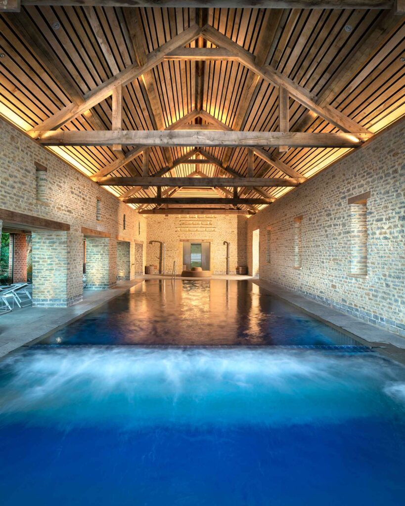 A large indoor pool in a former stable yard with exposed wooden beams overhead at The Newt in Somerset, Bruton, United Kingdom