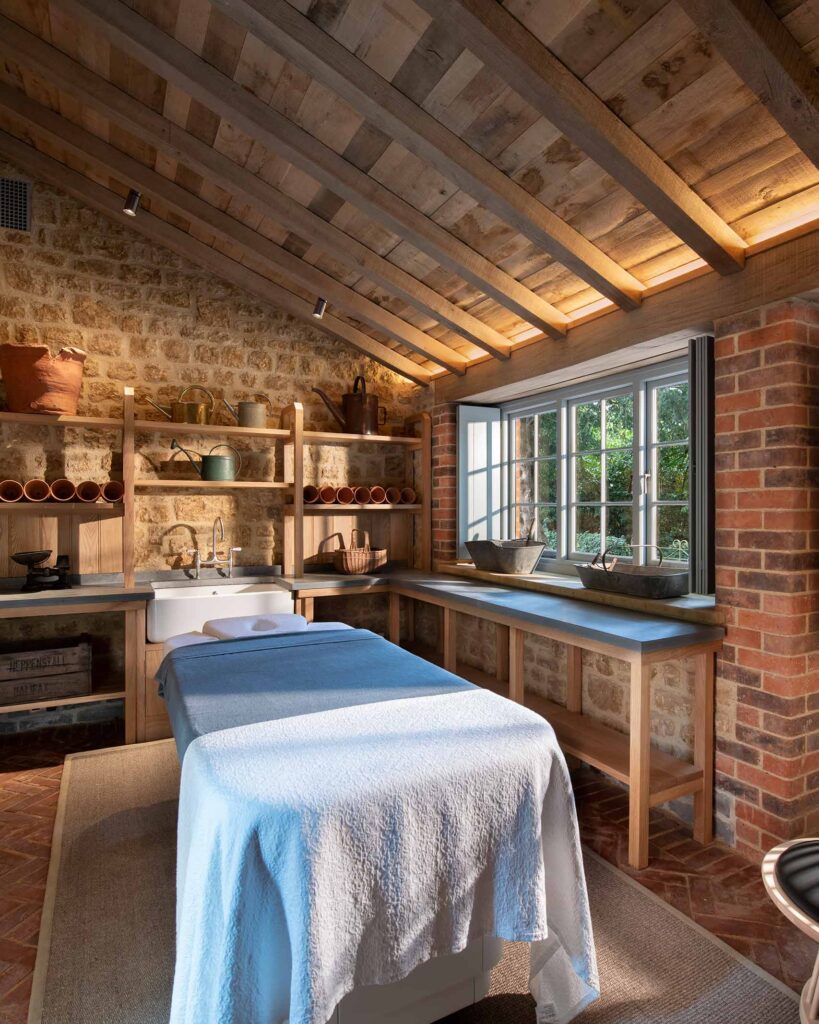 A rustic massage room with exposed brick walls and a window into the garden at The Newt in Somerset, Bruton, United Kingdom