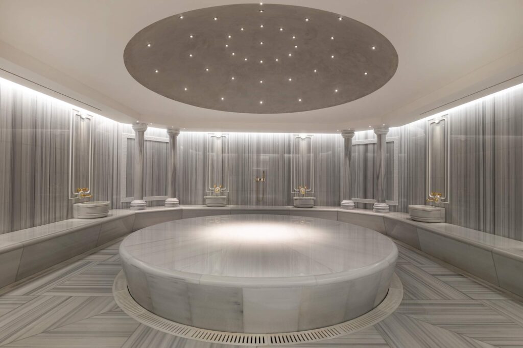A round, marble hammam stone inside the brightly lit Turkish bath at The Peninsula, Istanbul, Türkiye