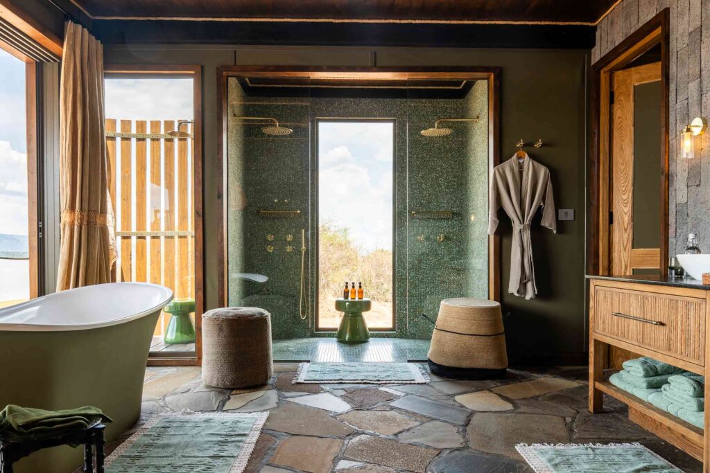 A freestanding bathtub and twin showers in a contemporarily designed accommodation at Wilderness Magashi Camp in Akagera National Park, Rwanda