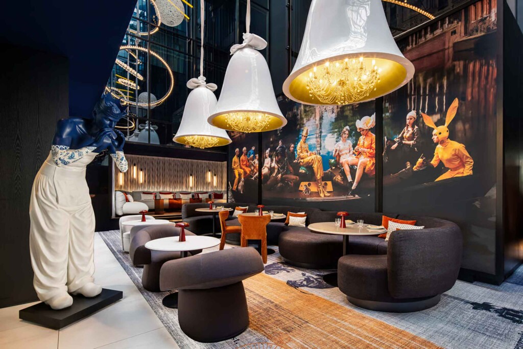 The lobby area of Dining area at Andaz Amsterdam Prinsengracht, with bellshaped chandelier coverings, sculptures and photographic mural art
