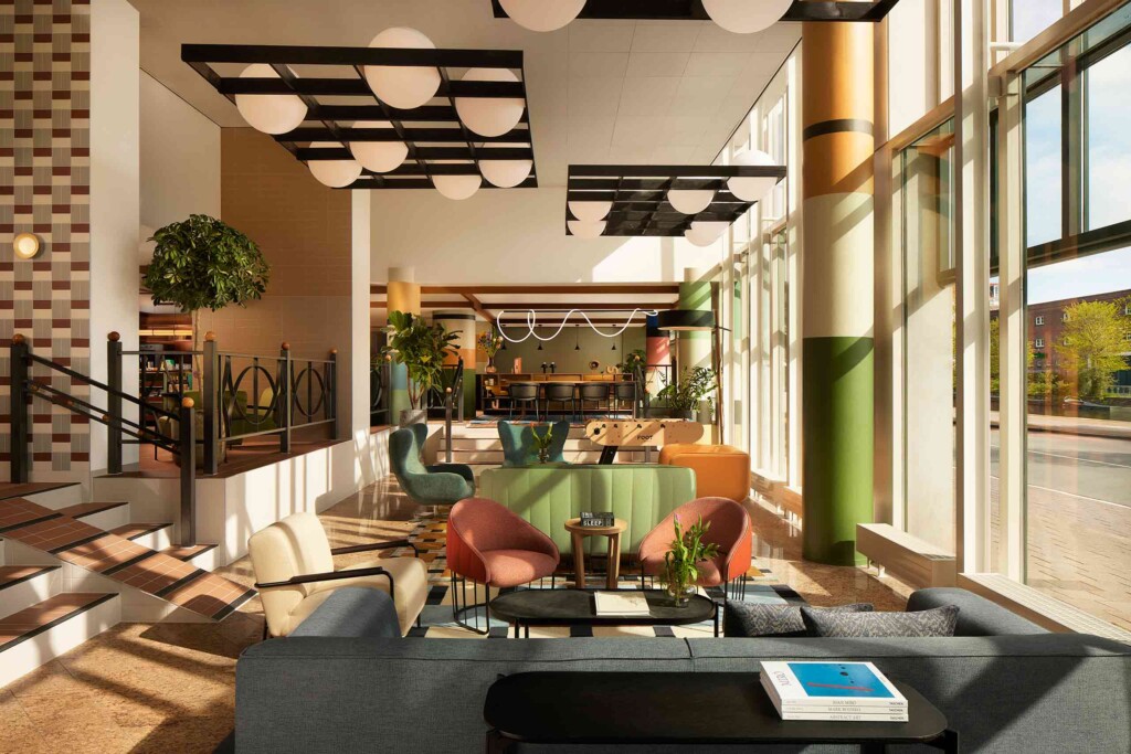 Lobby of Avani Museum Quarter Amsterdam, with designer grey, orange, cream and green furniture and statement designer lighting